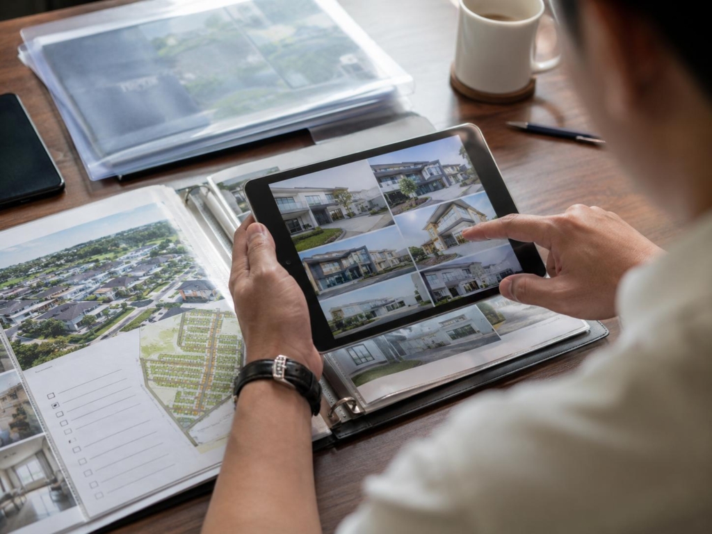 Homebuyer reviewing subdivision house designs and developer portfolio on a tablet
