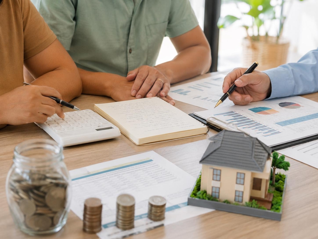 Homebuying budget discussion with calculator, savings, and house model