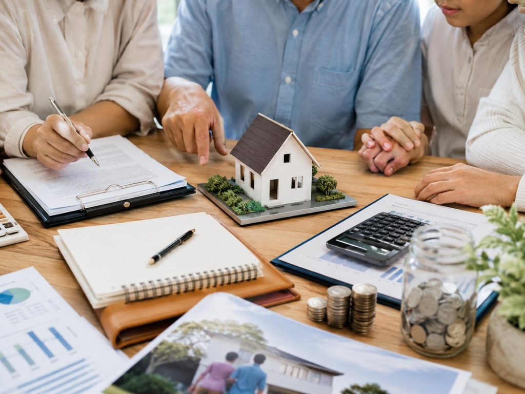 Family reviewing house model, financial documents, and savings plans